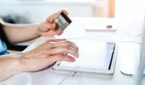 A man is holding a credit card on a tablet.