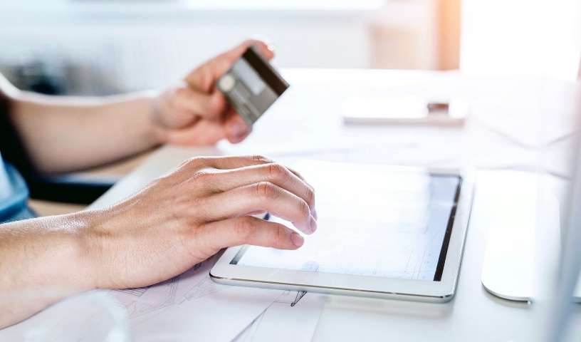 A man is holding a credit card on a tablet.