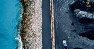 An aerial view of a truck on a road near the ocean.