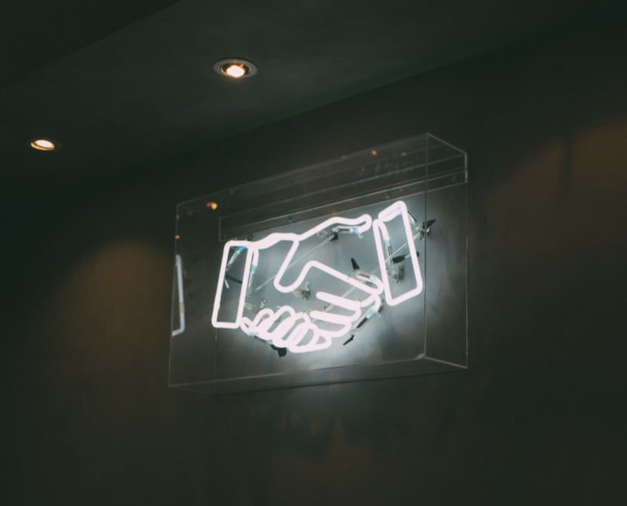 A neon sign with a handshake on it.