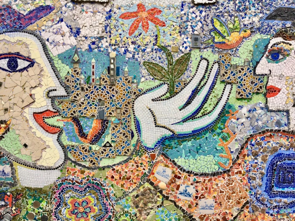 A mosaic of hands and flowers on the wall.